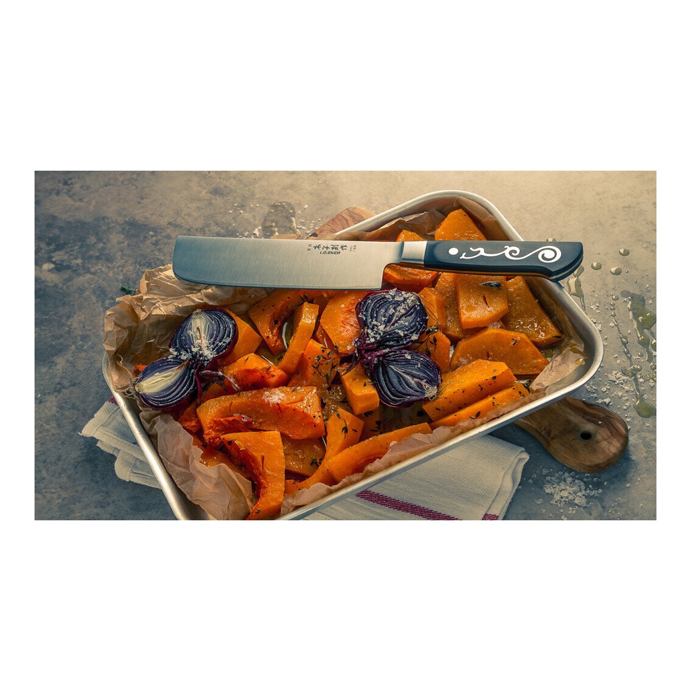 Tray of roasted orange squash and purple onion chunks, parchment lining, with a chef's knife across the top.